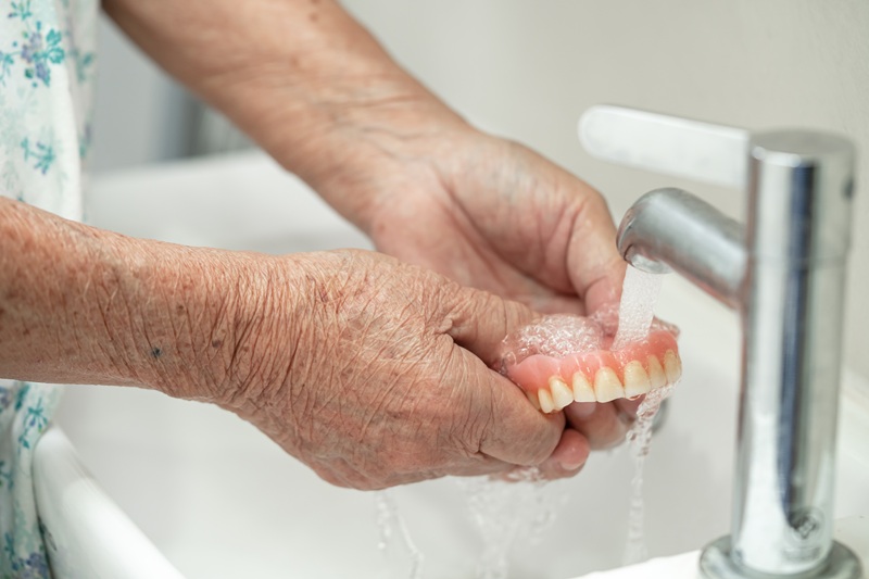Asian senior or elderly old woman patient holding and washing denture
