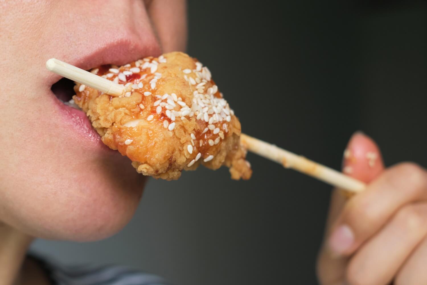 Someone eating a fried chicken on a stick