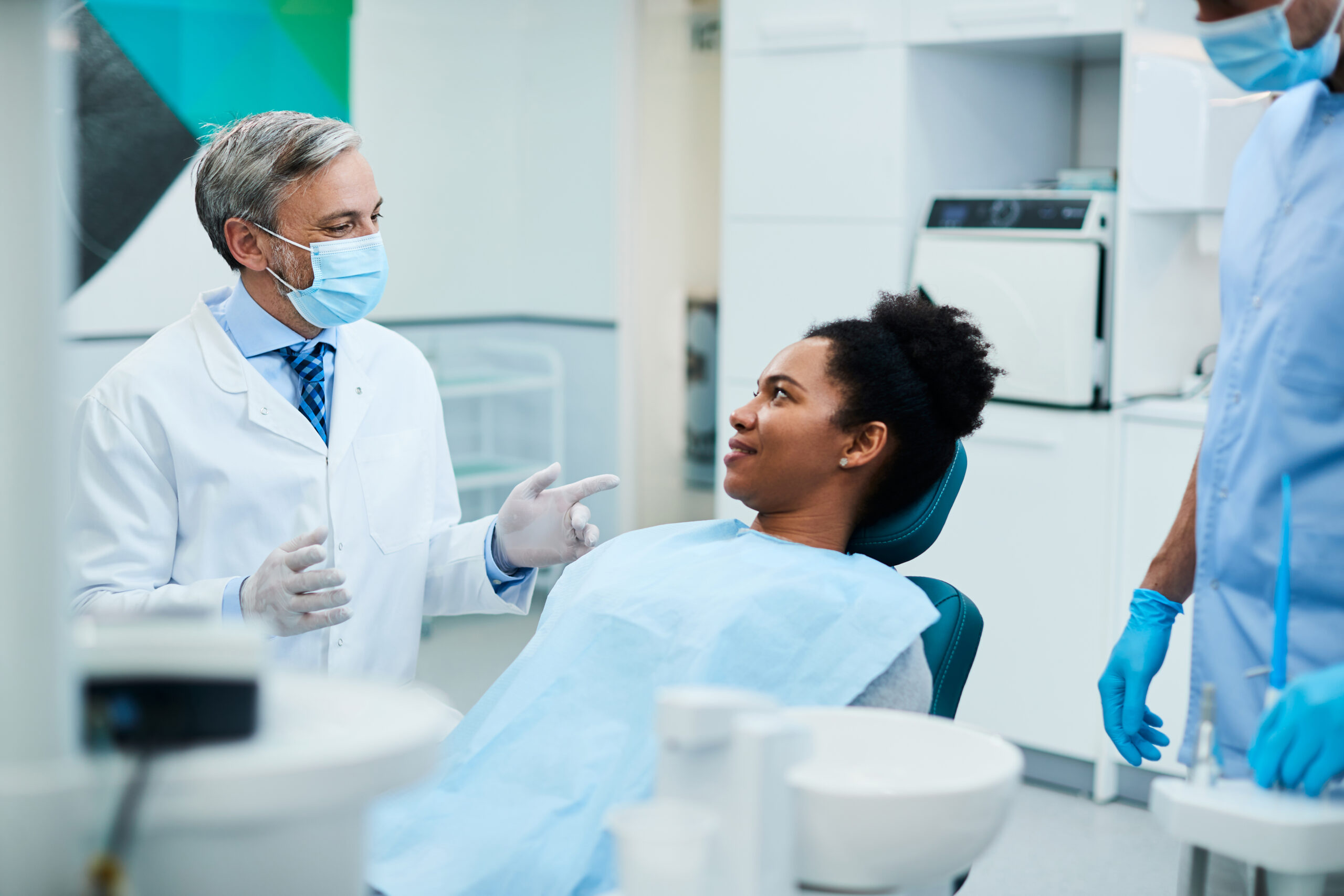 Smiling dentist talks with a relaxed female patient in the dental chair to ease her dental anxiety before treatment